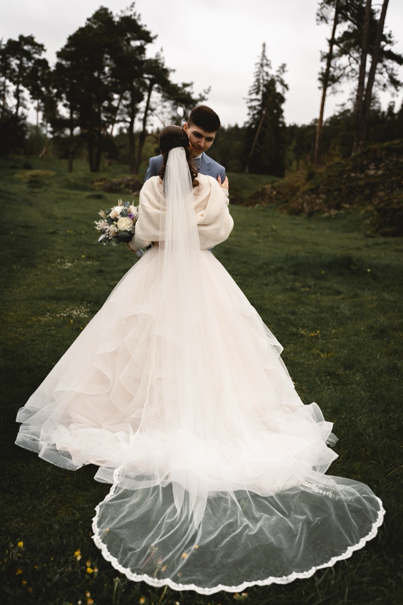 Bride from behind, long veil and train on a lawn